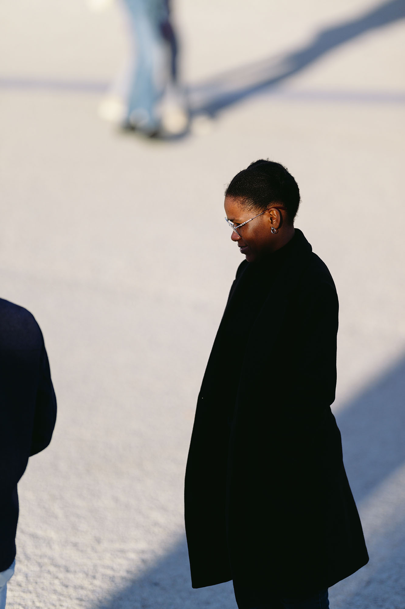 Last rays of winter sun on the face of the woman in black coat at the Praca do Comercio in central Lisbon, Portugal