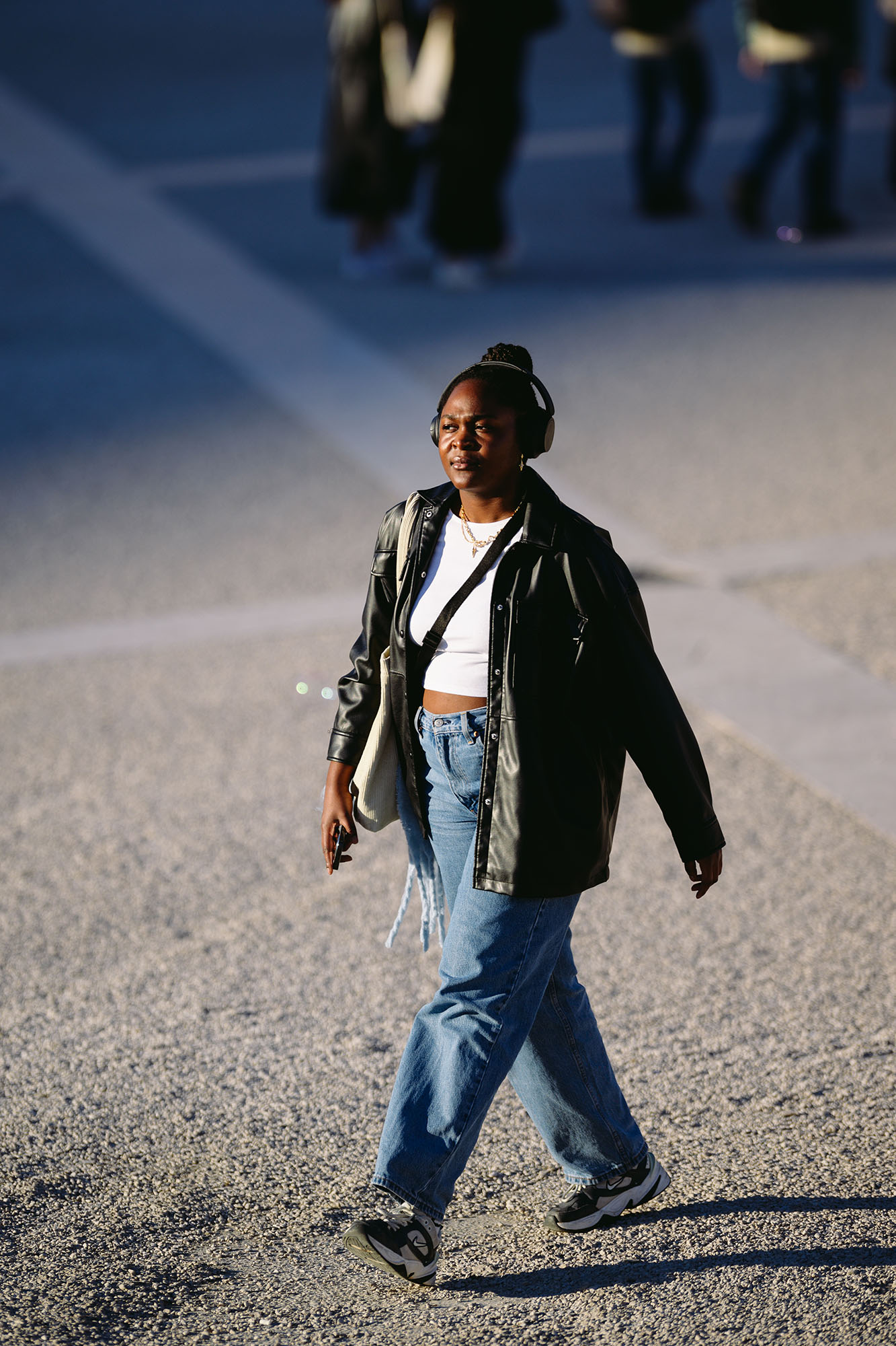 Woman with headphones walking in the eveing sun at the Praca do Comercio in central Lisbon, Portugal