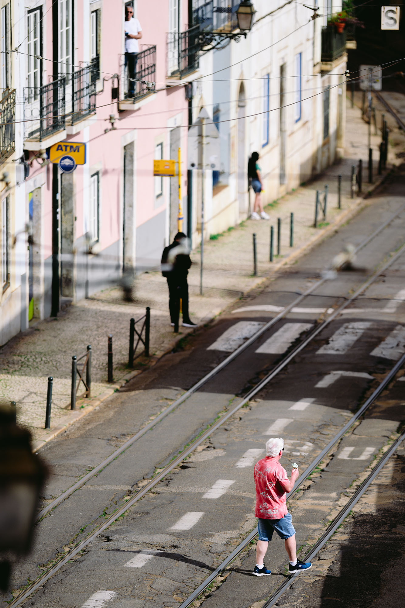 Tourist in a pink shirt with a light green ice-cream in a cone in Alfama area of Lisbon, Portugal